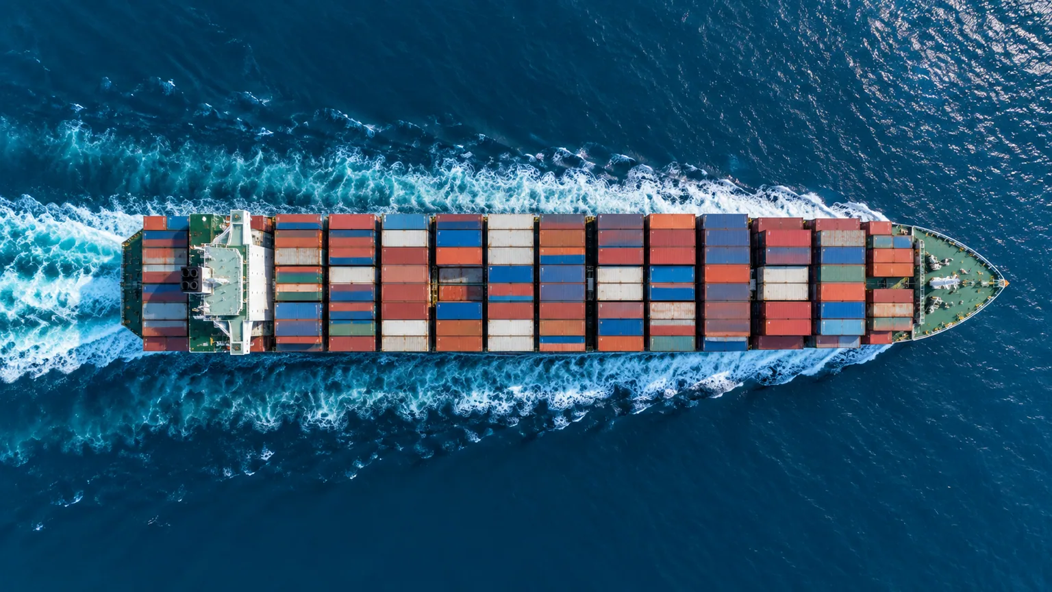 Top-down view of a container ship moving through blue water