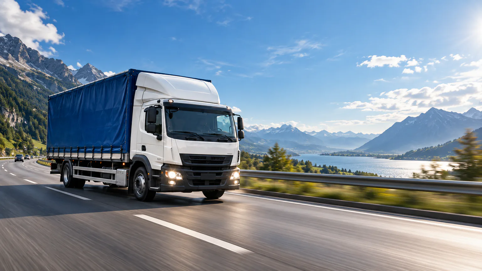Camion alb cu prelată albastră în lumină de zi, pe un drum alpin